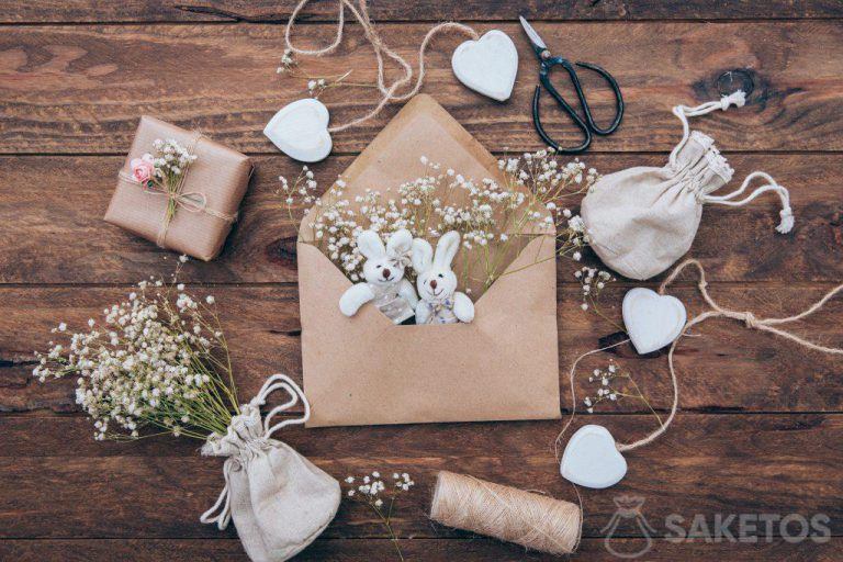 Una bolsa de lino con un yeso, conejitos de peluche en un sobre y un regalo envuelto en papel gris.
