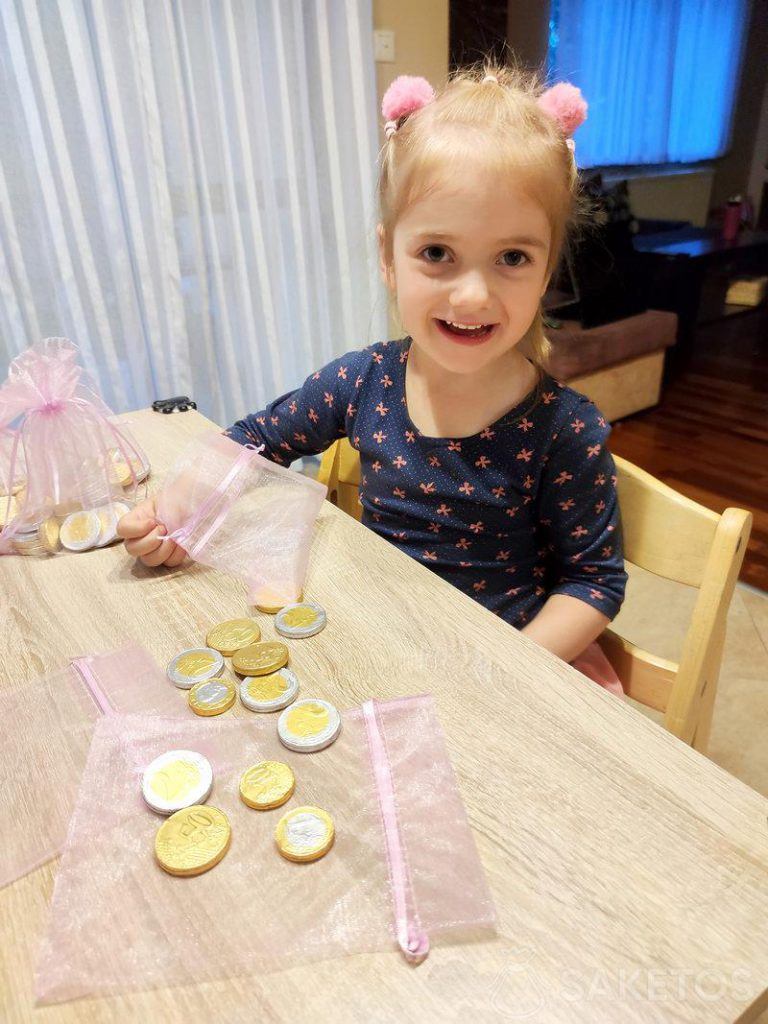 Una niña llena bolsas de organza con monedas de chocolate