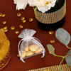 Pequeñas bolsas de organza 10x13 cm con almendras doradas en una mesa elegante.