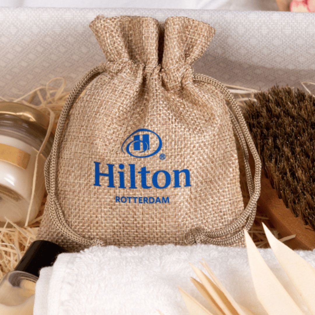 Saco de yute con el logo azul de Hilton, apoyado sobre una toalla.