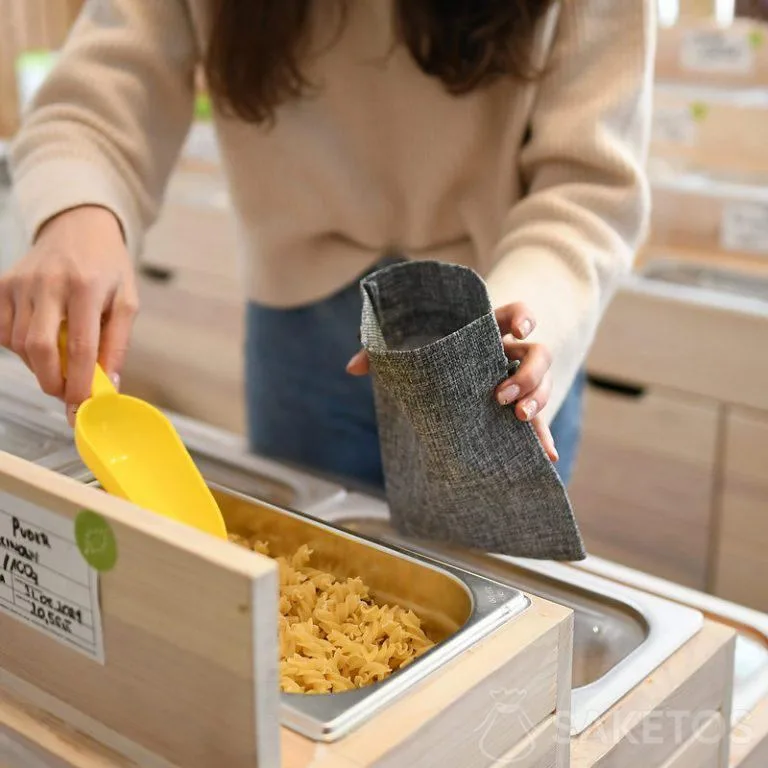 Una mujer va de compras, colocando productos sueltos en bolsas de la compra duraderas - envases de yute reutilizables