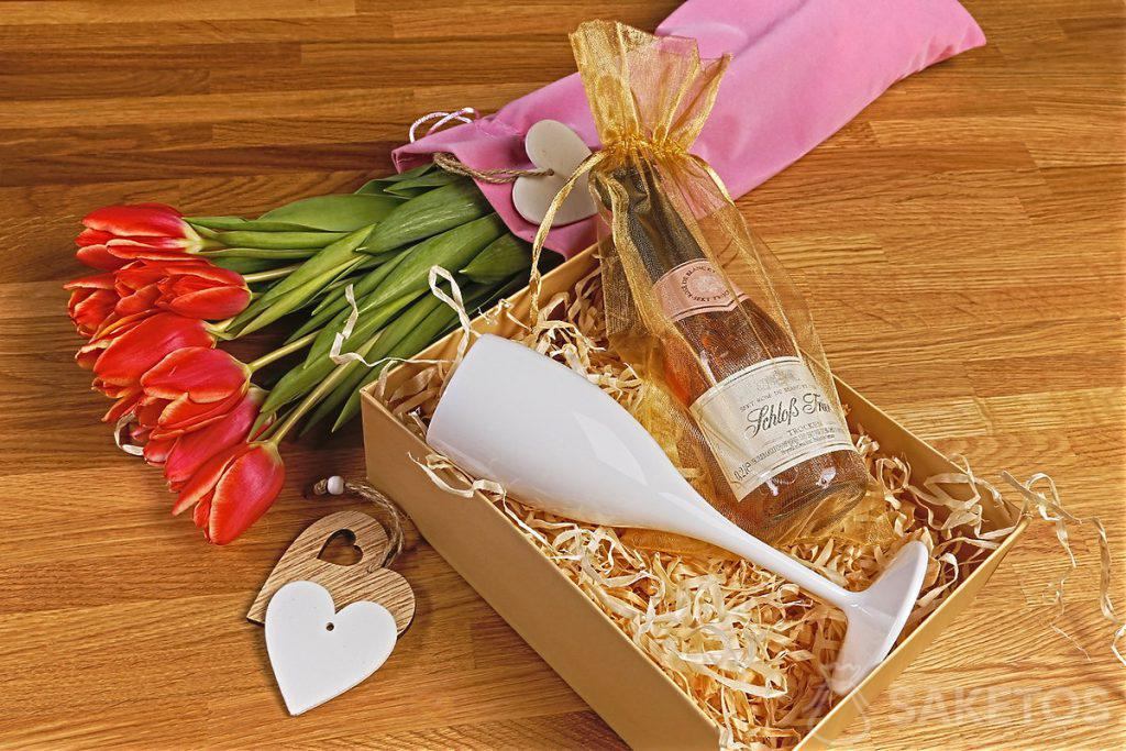 Flores en una bolsa de terciopelo y un box de regalo con una copa para el Día de la Mujer