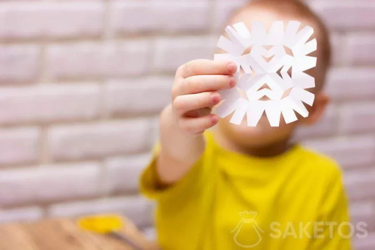 Niño recortando un copo de nieve de papel