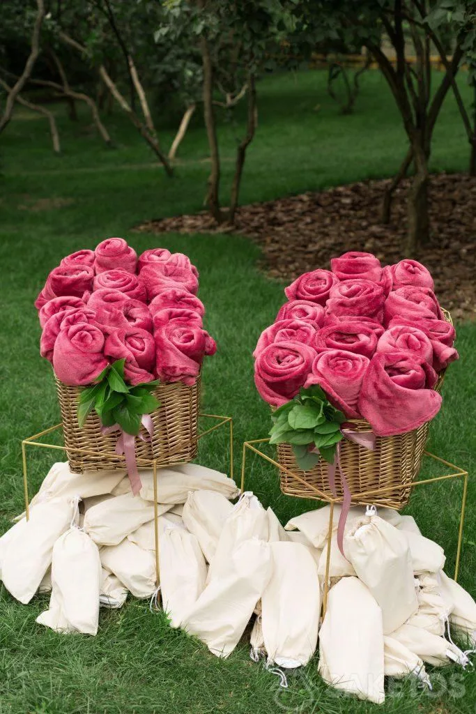 Mantas decorativas enrolladas y pantuflas en bolsas de lino preparadas para los invitados de la boda.