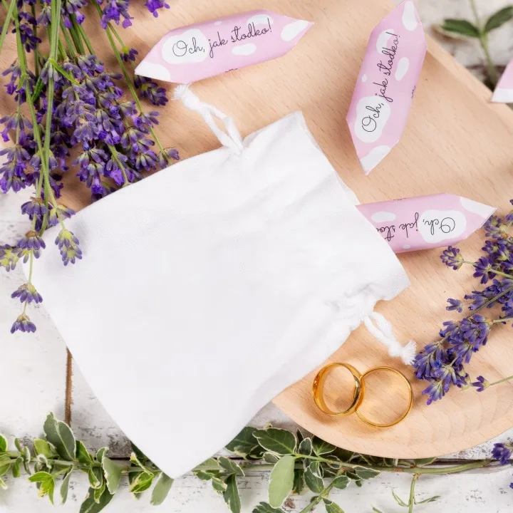 Elegante saquito de raso blanco junto a alianzas de oro para boda.